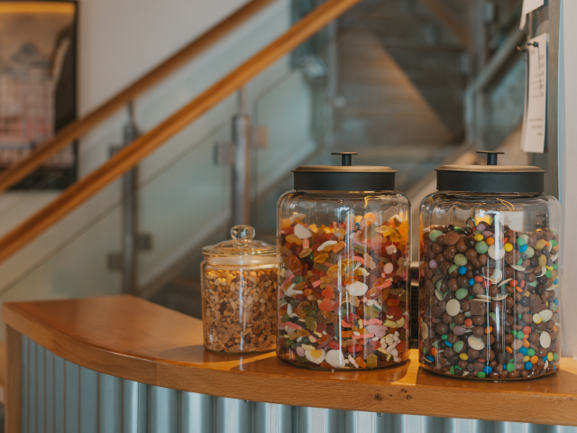 A photograph of the Mezzanine Bar of Richard Booth's Bookshop Cinema. On the counter, there are sweets, chocolates and nuts in jars, which are available to purchase for cinema guests. The image gives potential customers reassurance that refreshment is available for cinema guests.